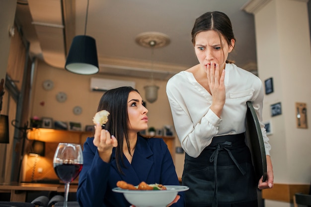 Amazed waitress look at salad bowl and cover mouth with hand