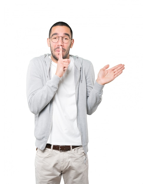 Amazed young man asking for silence gesturing with his finger