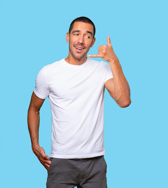 Amazed young man making a gesture of calling with the hand