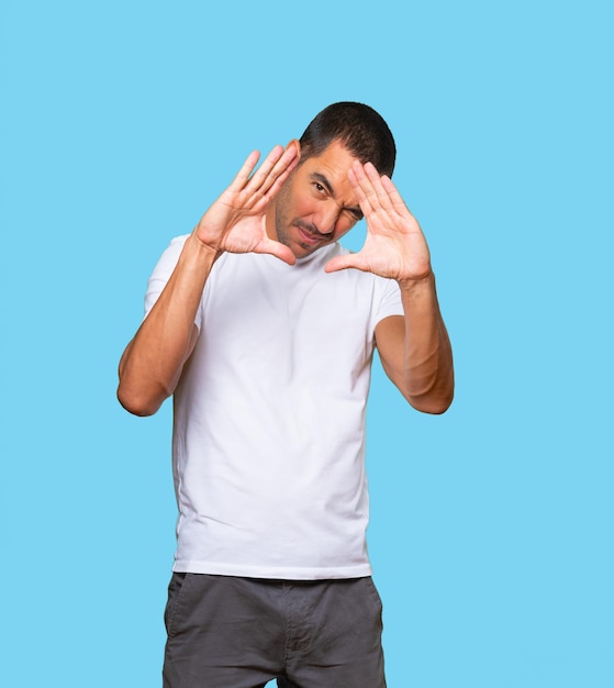 Amazed young man making a gesture of taking a photo with the hands