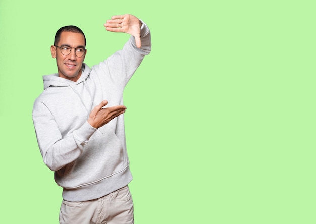 Amazed young man making a gesture of taking a photo with the hands