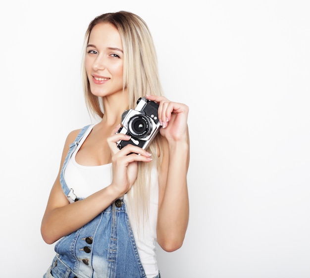 Amazed young pretty woman holding camera over white  background.