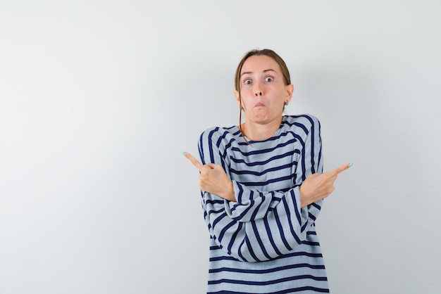 Amazed young woman crossing her arms and showing both sides on white background