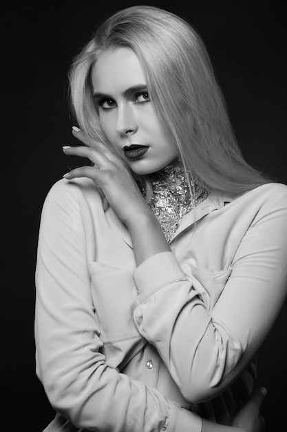 Amazing blond model posing at studio with bright makeup and foil on her neck. Monochrome shot