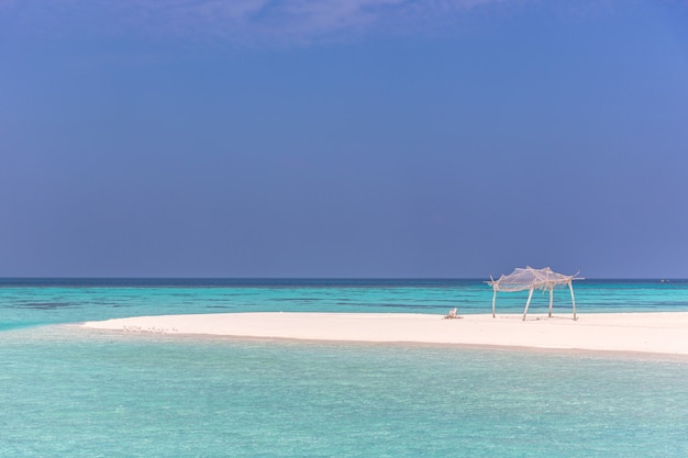 Amazing blue water in a desert island in a blue sky day with a little wood hut