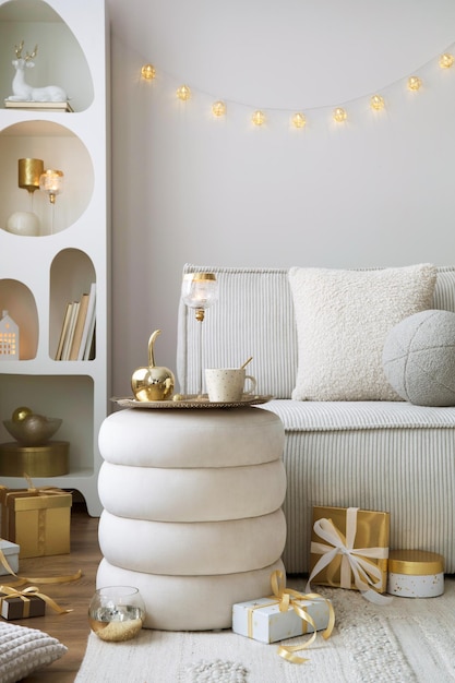 Amazing composition on white design shelf with christmas decoration lights gifts lanterns deer candles stars white corduroy sofa and pouf Santa claus is coming Home decor Template