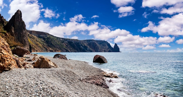 Amazing landscape on coast of blue ocean in clear sunny weather. Sea waves lash line impact rock on beach. Cozy backgrounds for site or large-resolution wallpaper. Concept of relaxation, recreation