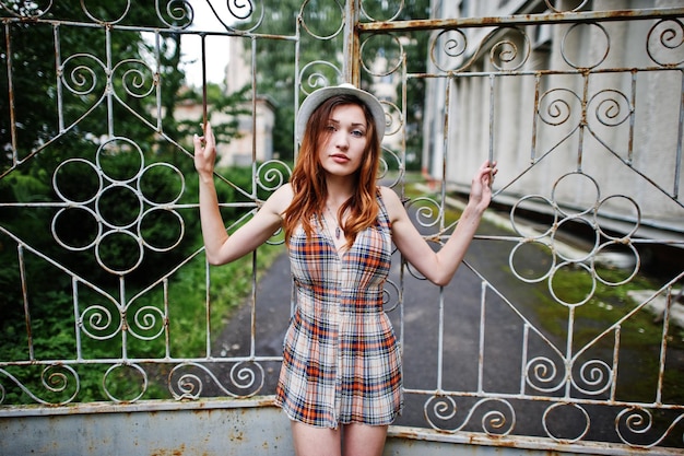 Amazing long legs with hig heels girl wear on hat against iron fence