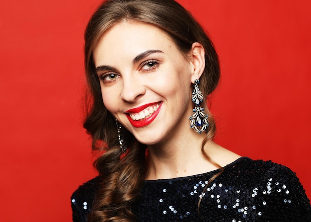 Amazing luxury woman in stylish party dress posing on red background