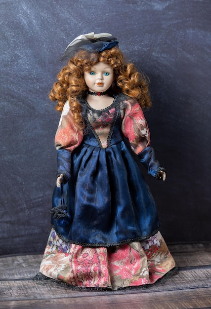 Photo amazing realistic vintage porcelain doll toy with blue eyes the doll dressed in a redblue dress and has a red hair