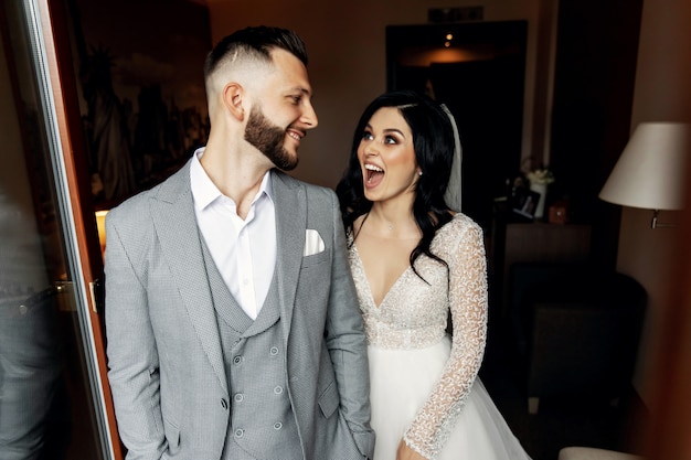 Amazing smiling wedding couple. Pretty bride and stylish groom.