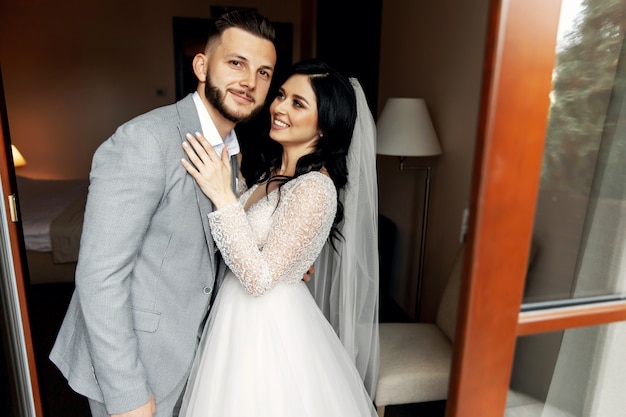 Amazing smiling wedding couple. Pretty bride and stylish groom.