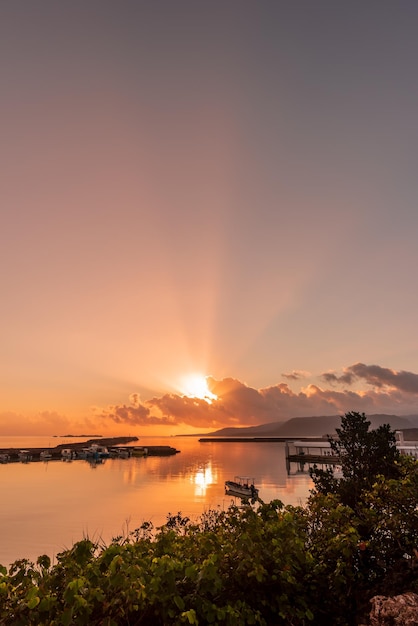 Amazing sunrise at seaside harbor sunbeams spreading in the sky boats on the smooth sea