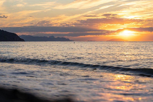 Amazing sunrise over the tropical beach. Yellow sun over sea. Orange colors waves. Nature background. Beautiful serene scene. Morning. Sunlight reflect on water surface