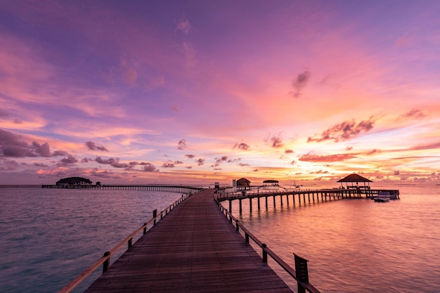 Amazing sunset at Maldives. Luxury resort villas seascape, fantastic colored sky clouds, vacation