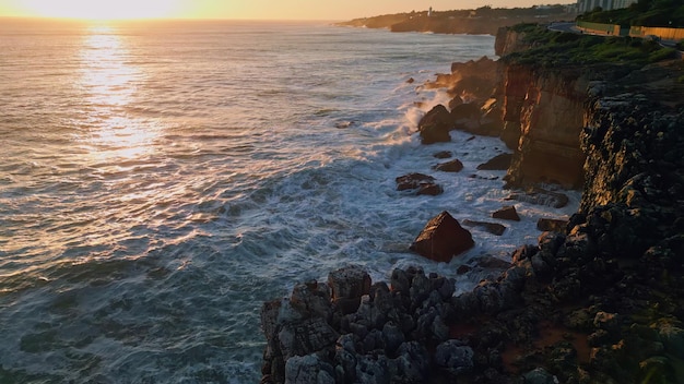 Amazing sunset sky foaming ocean waves washing rocky coast aerial stormy water