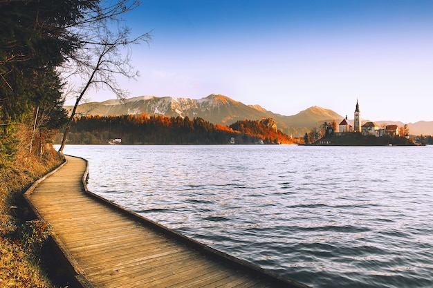 Photo amazing view on bled lake on sunrise with wooden promenade autumn winter in slovenia europe