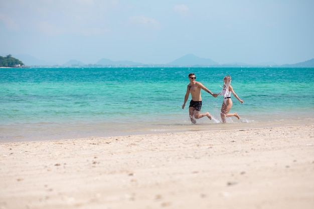 Amazing young couple runs on the beach hand in hand