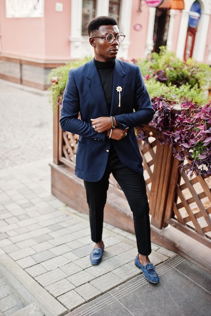 Amazingly looking african american man wear at blue blazer with brooch black turtleneck and glasses posed at street Fashionable black guy