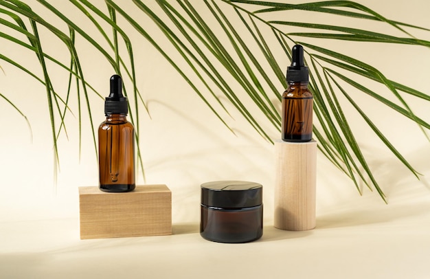 Amber cosmetic bottles with pipette on wooden geometric pedestal podiums product packaging with natural palm leaves anti aging serum with peptides cosmetics mockup spa concept