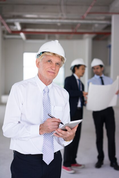 Ambitious architect in hardhat viewing building site and thinking of design.