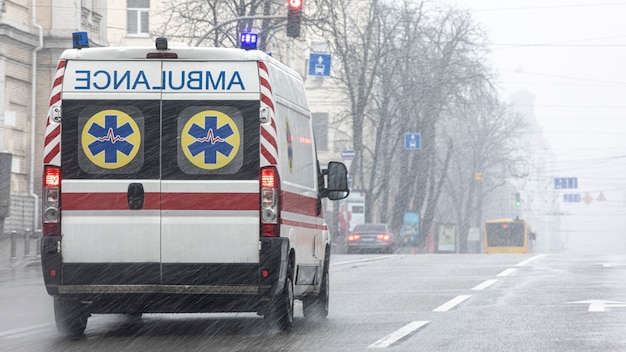 An ambulance took the patient to the clinic with the turn signals on. Bad weather outside, rain with wet snow.