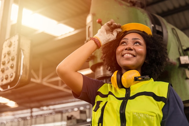 American black women teen worker enjoy working labor in industry factory with heavy steel machine happy smiling