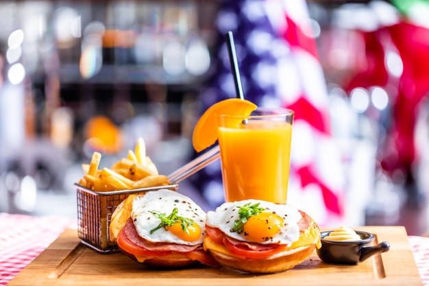 American breakfast sandwich with fried egg french fries and orange juice