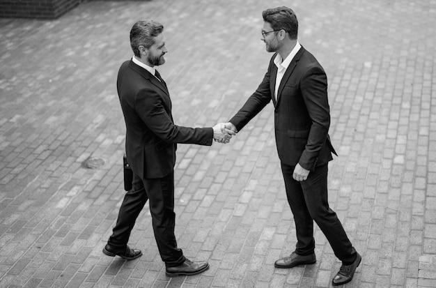 Photo american business man shaking hands with partner successful teamwork two business men shaking hands on street business men in suit shaking hands outdoors handshake between two business men