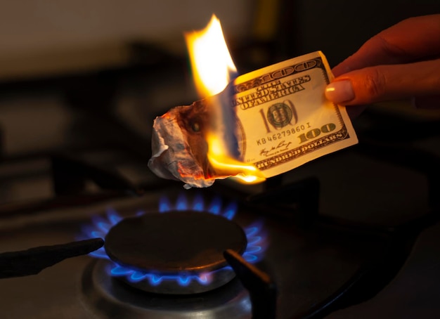 The American dollar is on fire Burning gas burner on the background of one hundred dollars The concept of gas price increase Expensive gas supply Selective focus