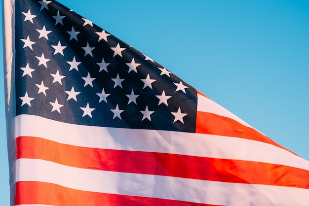 American flag in a blue sky, close up. Symbol of Independence Day fourth of July in USA