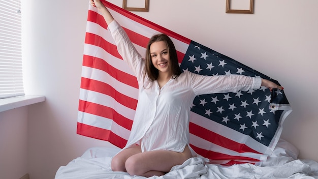 American flag day girl in the bedroom holds the symbol of independence of the united states in her hands behind her back USA Independence Day