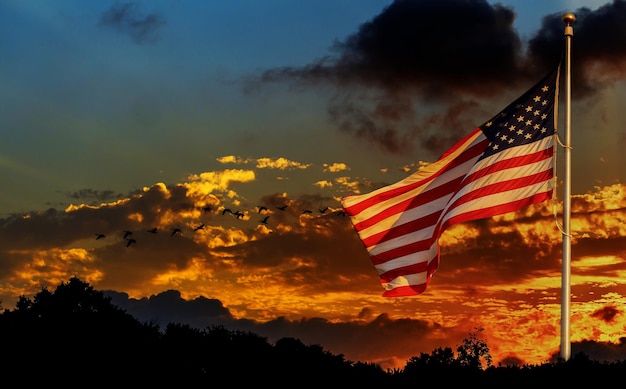 American flag on flagpole waving in the wind against clouds american flag in front of bright sky