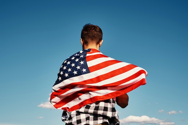 American flag outdoors man holds usa national flag against blue cloudy sky th july independence day