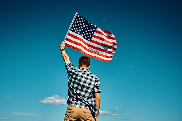 American flag outdoors man holds usa national flag against blue cloudy sky