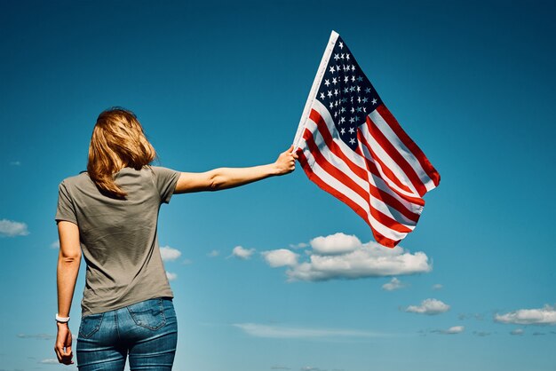 American flag outdoors woman holds usa national flag against blue cloudy sky th july independence day