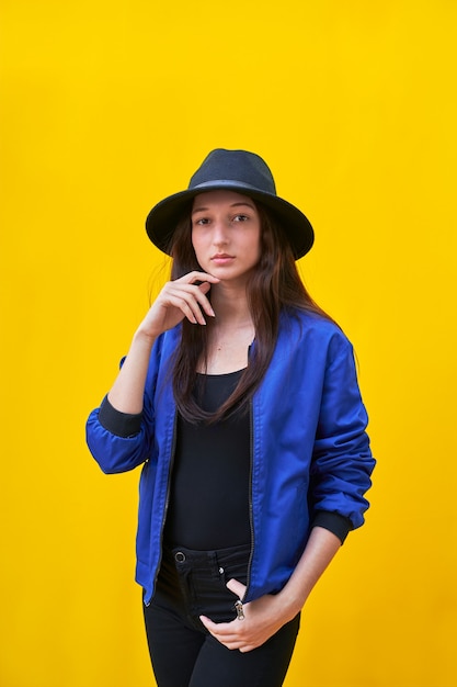 American flat young caucasian girl portrait in black hat and blue jacket, hand over face