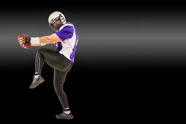 American football player in motion with the ball on a black background with a light line copy space The concept of the game is American football movement