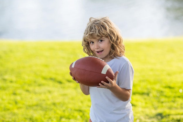 American football portrait of boy holding american football ball in park