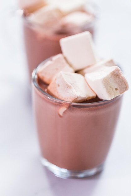 American hot chocolate topped with large marshmallow in glass cup.