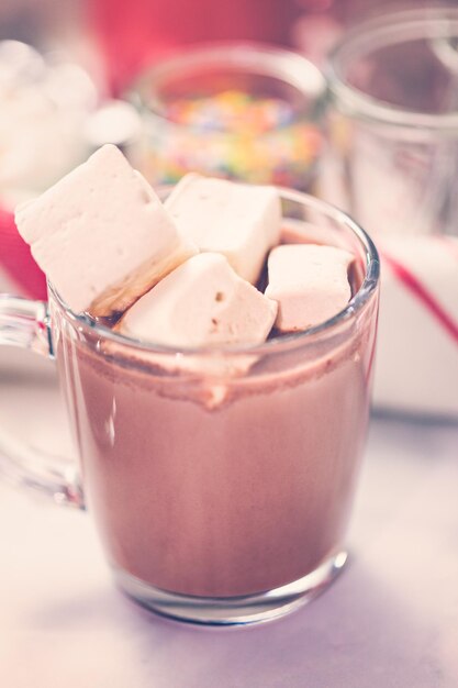 American hot chocolate topped with large marshmallow in glass cup.