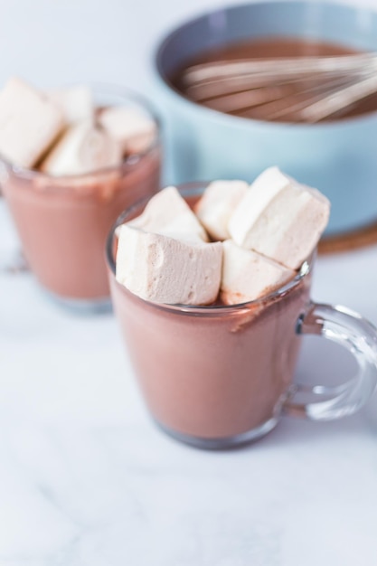 American hot chocolate topped with large marshmallow in glass cup.