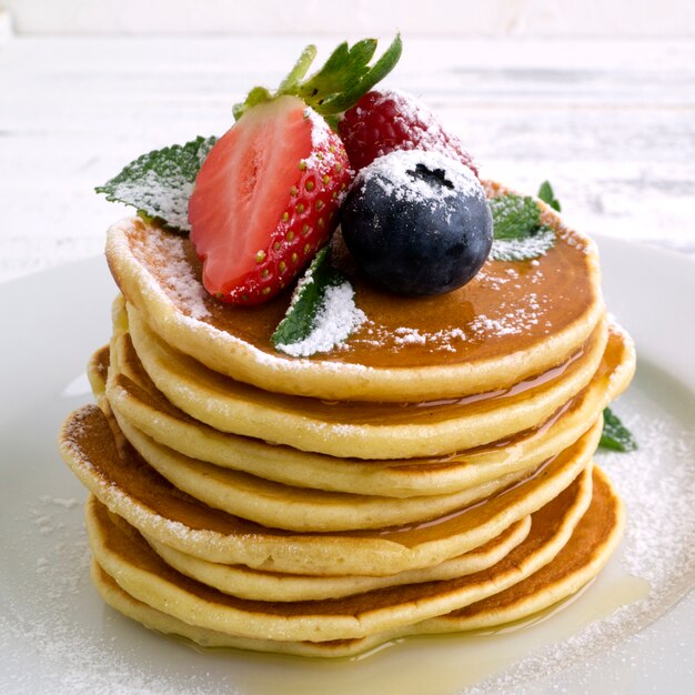 American pancakes with berries on a light background.