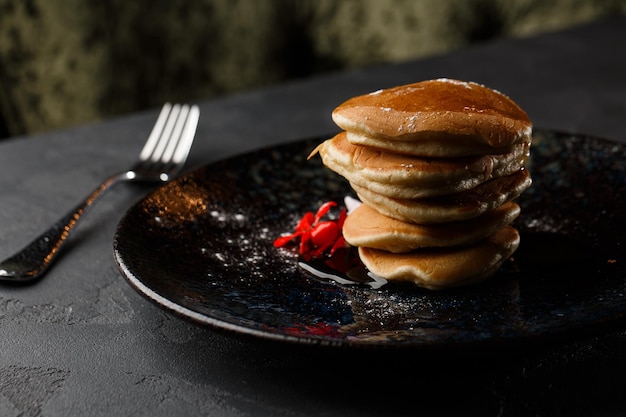 American pancakes with berries and maple syrup on black plate isolated on dark background cafe menu