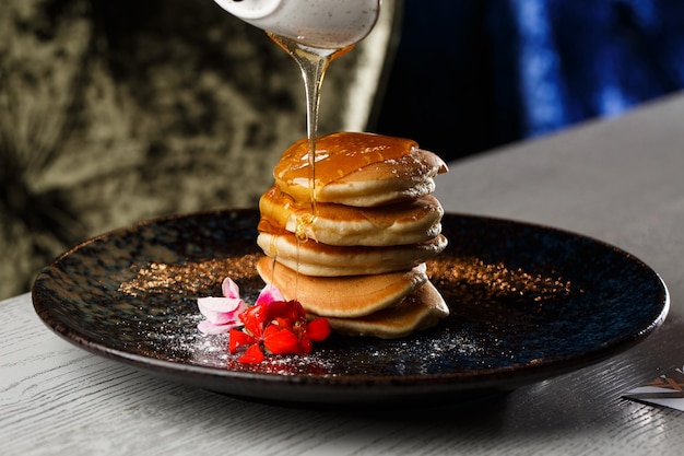 American pancakes with berries and maple syrup on black plate isolated on dark background cafe menu