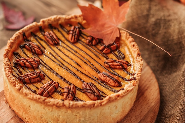 American pumpkin pie, decorated with chocolate and pecan nuts on a wooden table