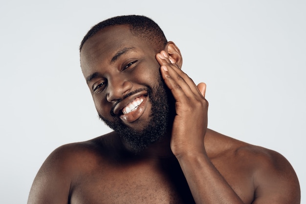 American smiling man is smeared with face cream.