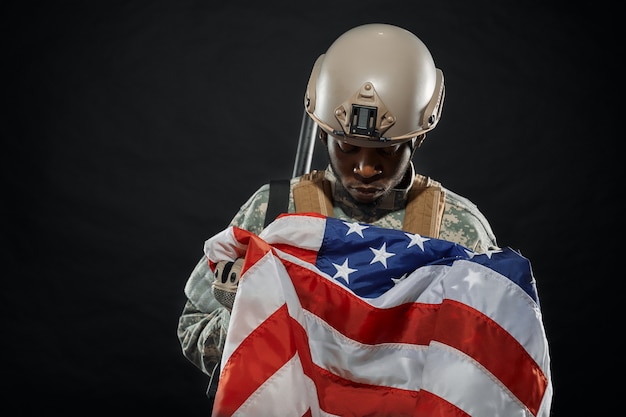 Photo american soldier holding nationals flag in hands.