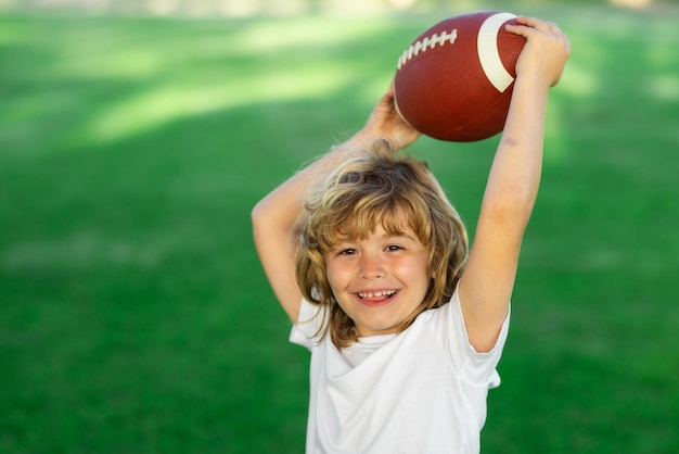 American style football Kids and sports Young boy playing american football Child holding rugby ball while playing american football in Summer park