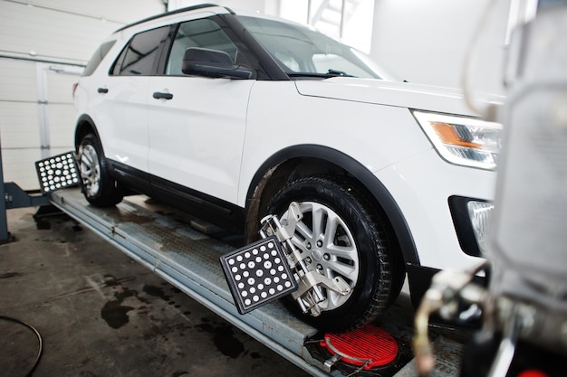 American SUV car on stand for wheels alignment camber check in workshop of service station